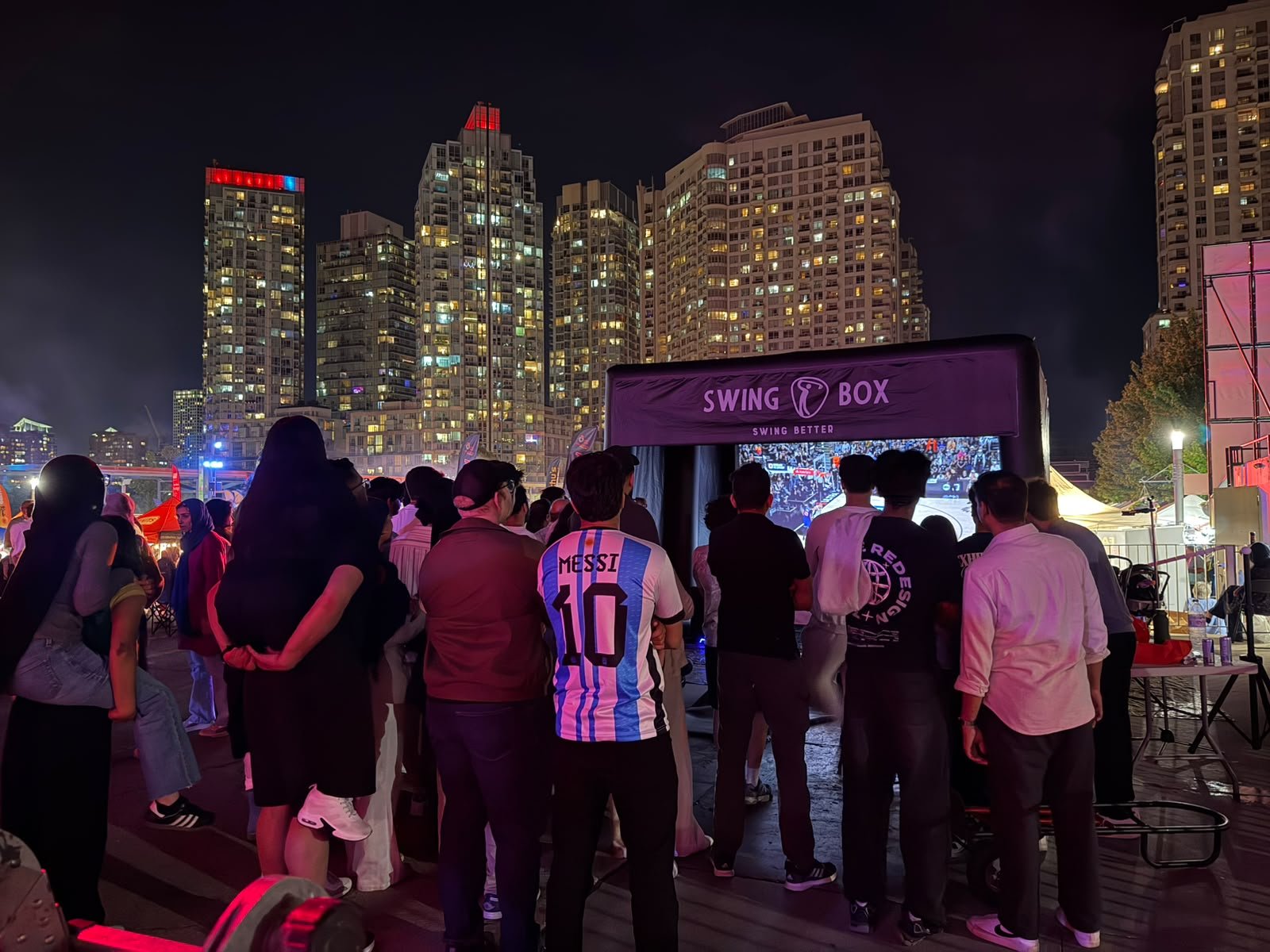 Large audience gathered around Swing Box during a real outdoor city event at night