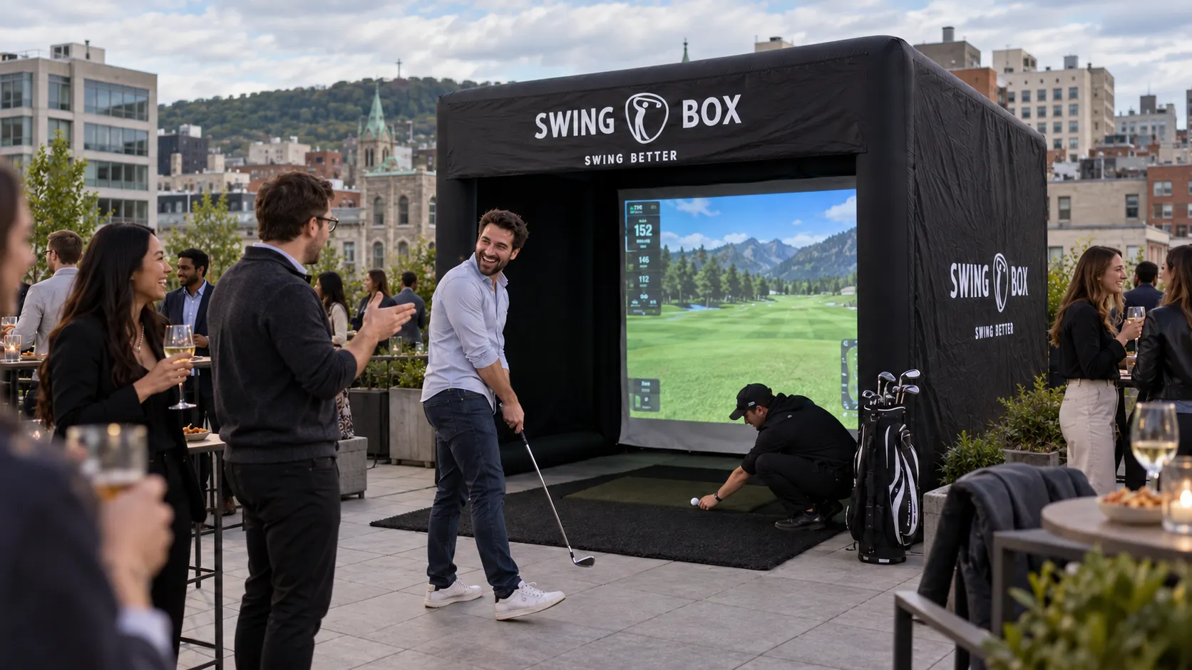 Coworkers laugh after a missed golf shot while a Swing Box attendant resets the ball at an office terrace event