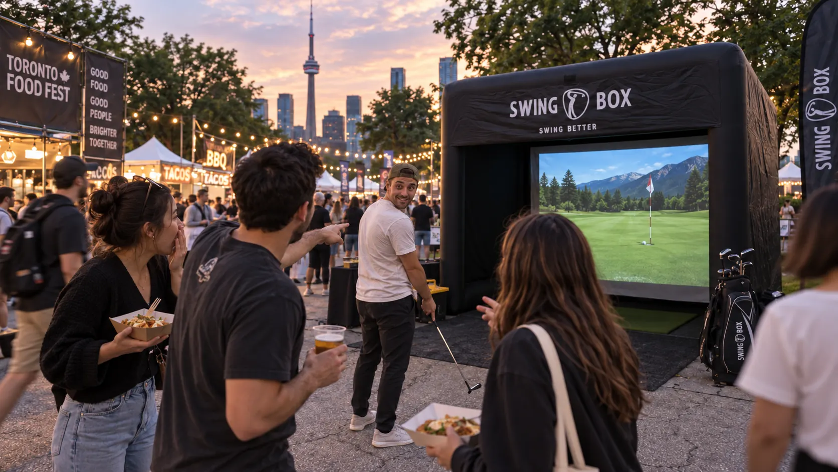 Festival visitors eating and talking beside a Swing Box golf simulator at a Toronto outdoor food event