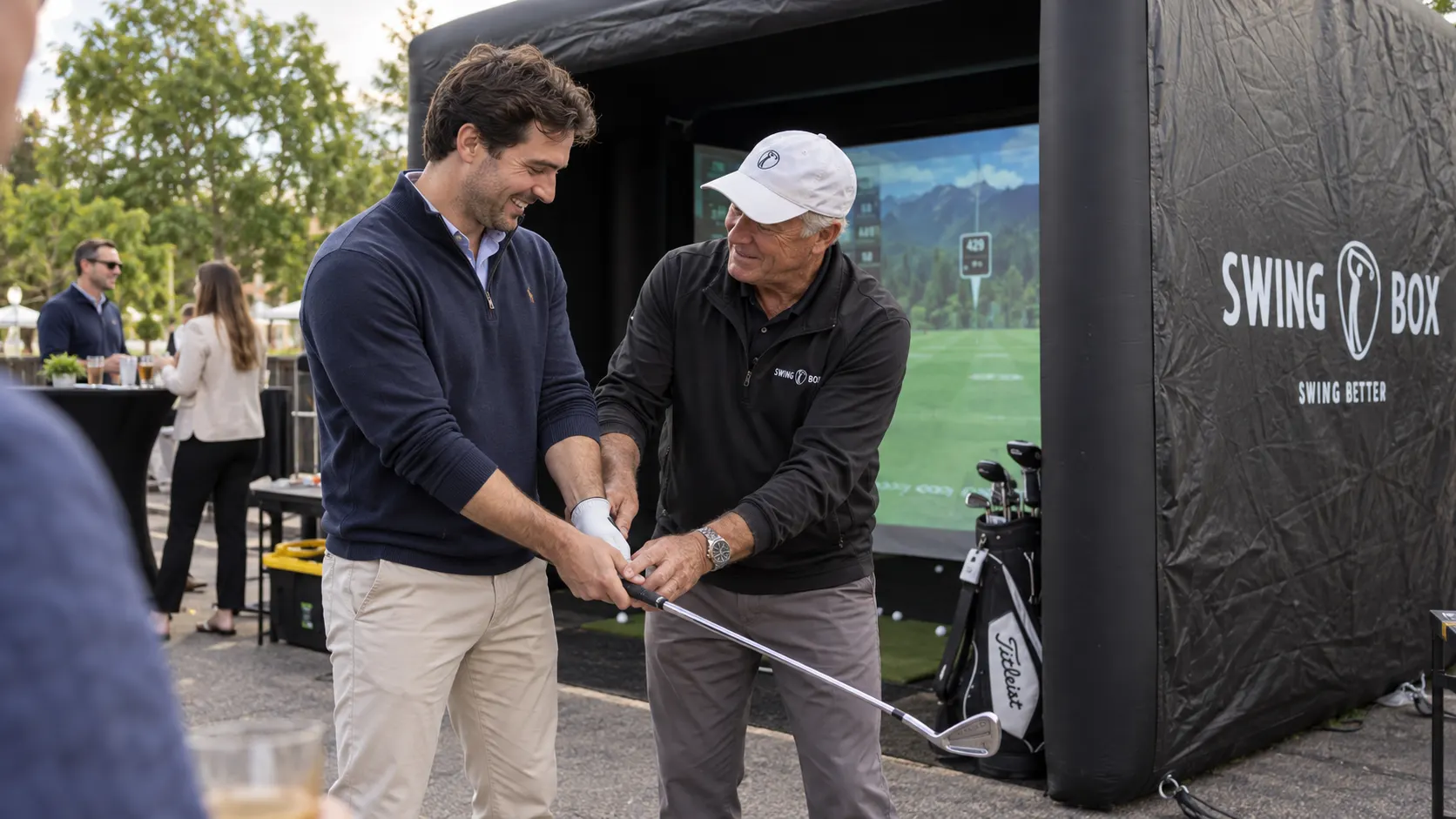 Swing Box staff member shows a corporate guest how to hold the golf club beside the inflatable simulator