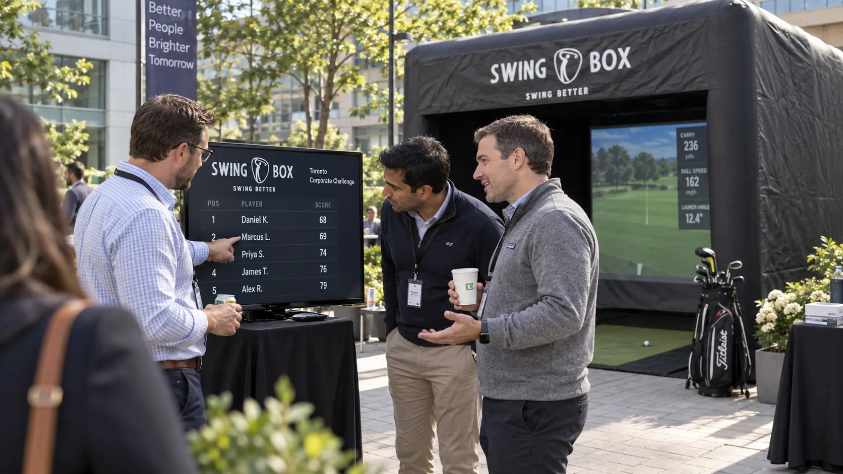 Three coworkers compare their scores on a Swing Box leaderboard during a daytime company event